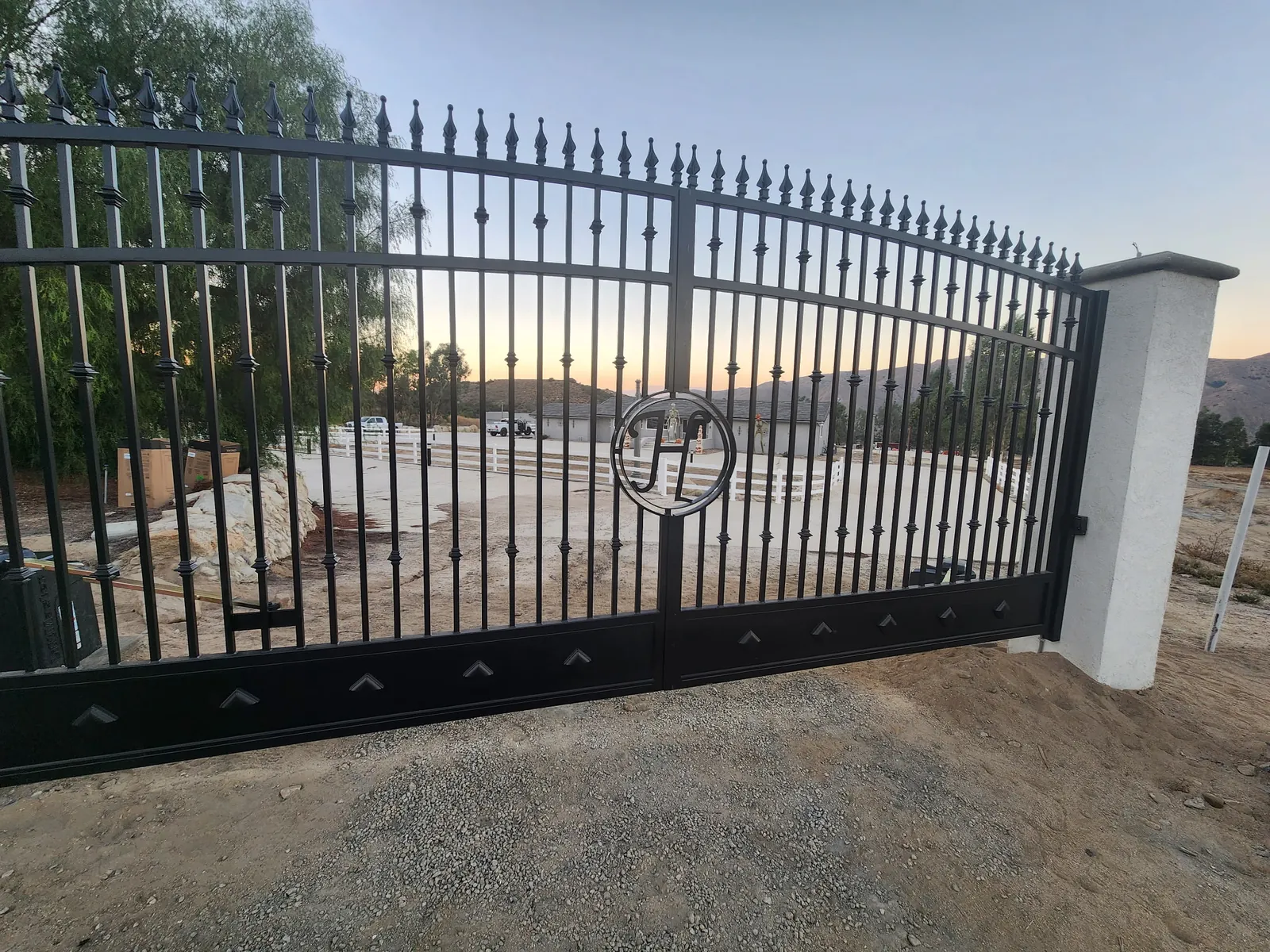 Black spear-top iron estate driveway gate with custom monogram, built by So Cal Ornamental Gates