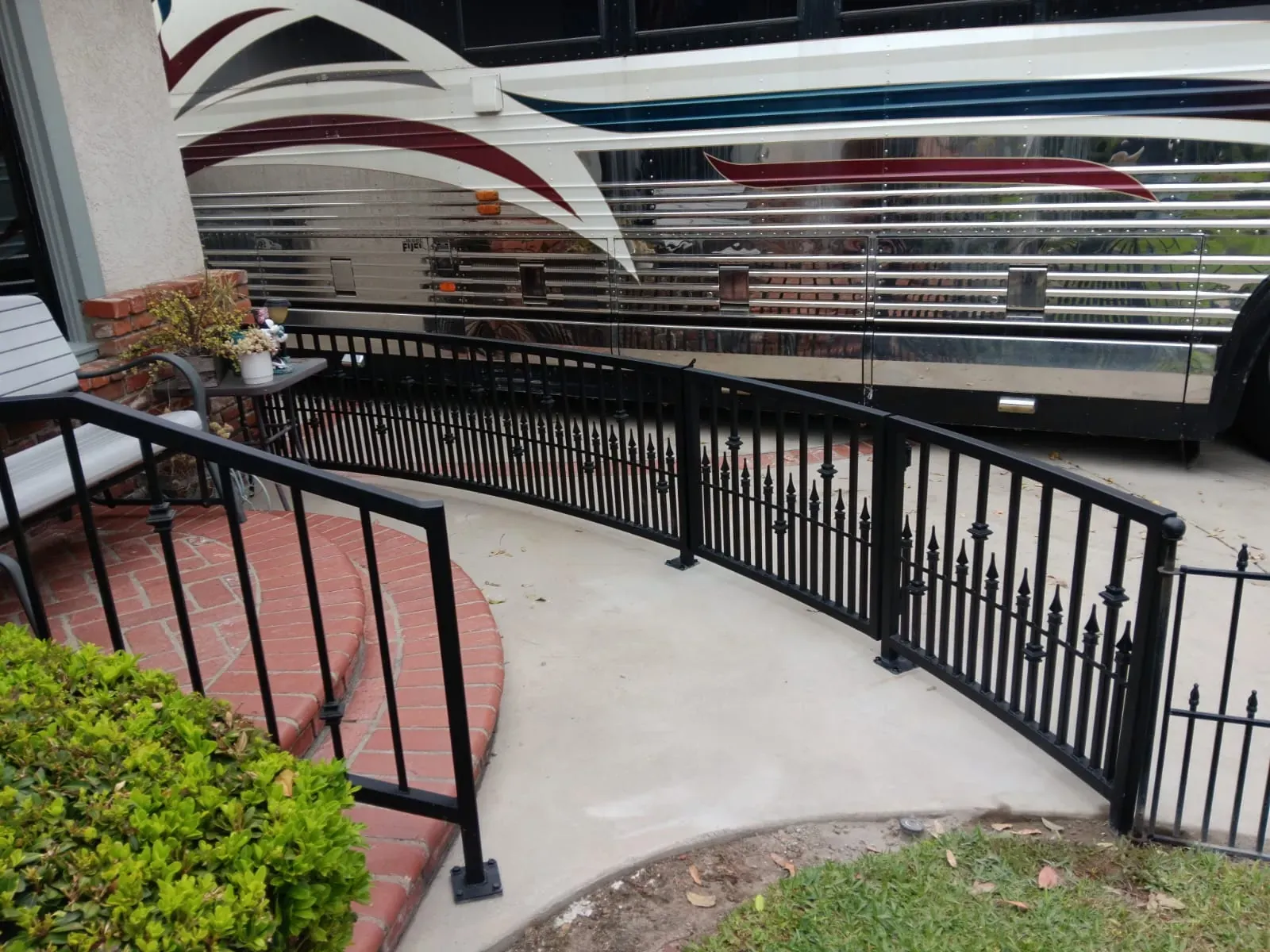 Curved black iron railing with spear pickets along a walkway