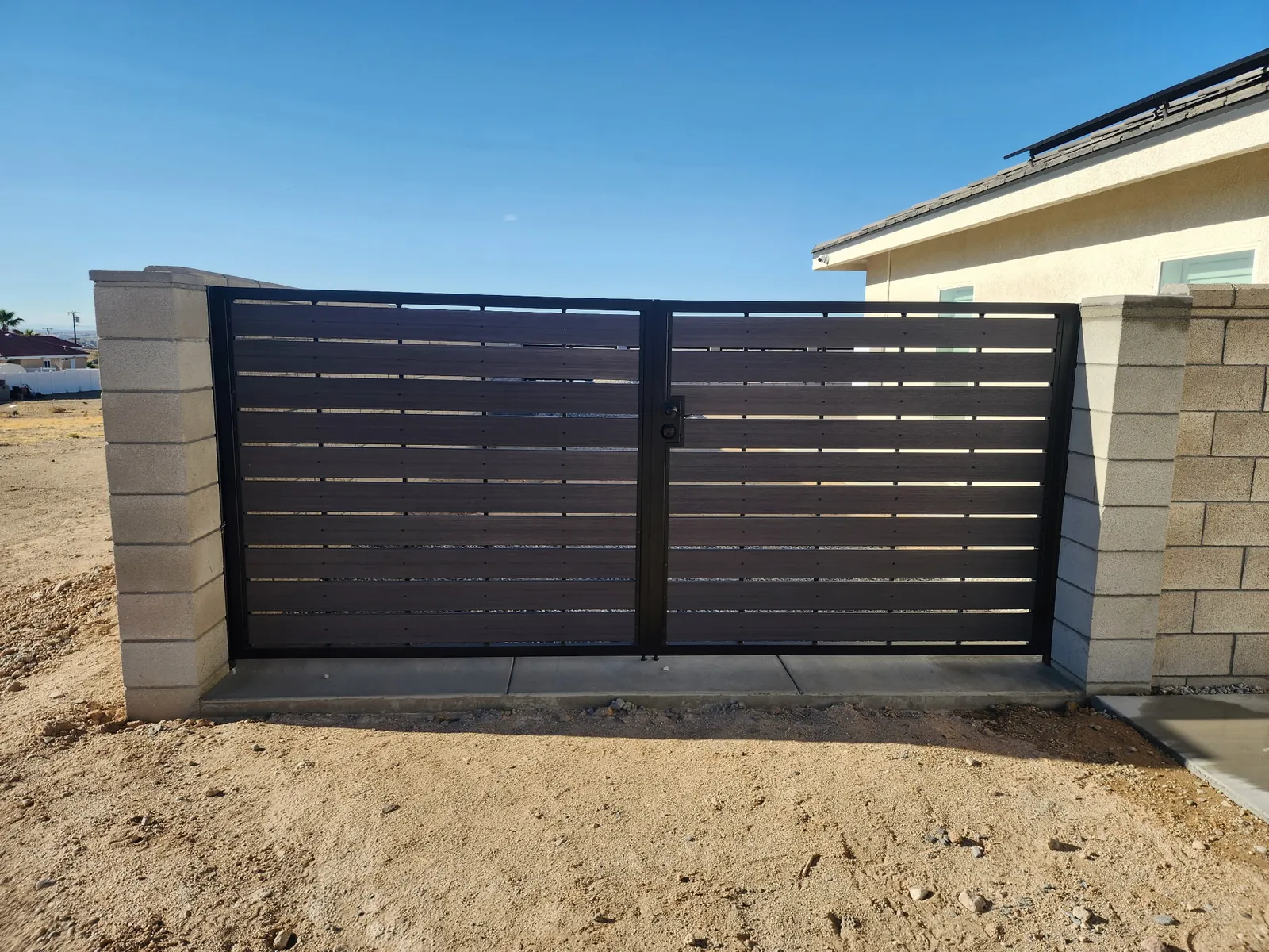 Dark wood-look horizontal slat double gate between block pillars