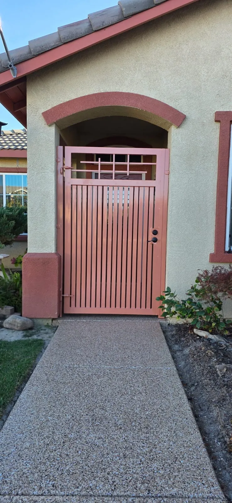 Terracotta vertical slat pedestrian gate with grid top at an arched entry
